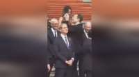 马斯克在人民大会堂前面带笑容，高举手机转圈拍摄